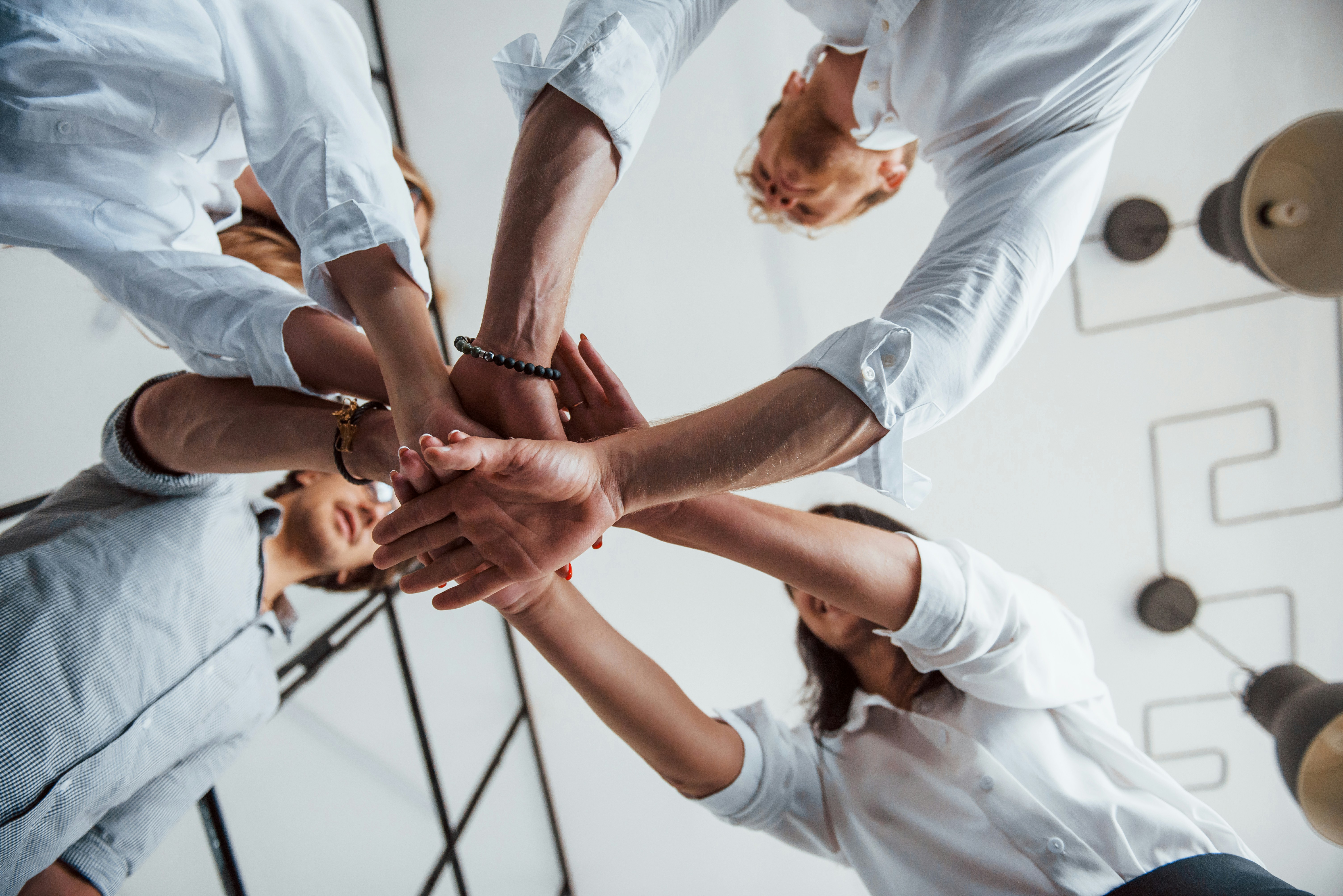 A diverse team uniting hands in a show of collaboration and trust, symbolizing effective leadership and management in a modern workplace.