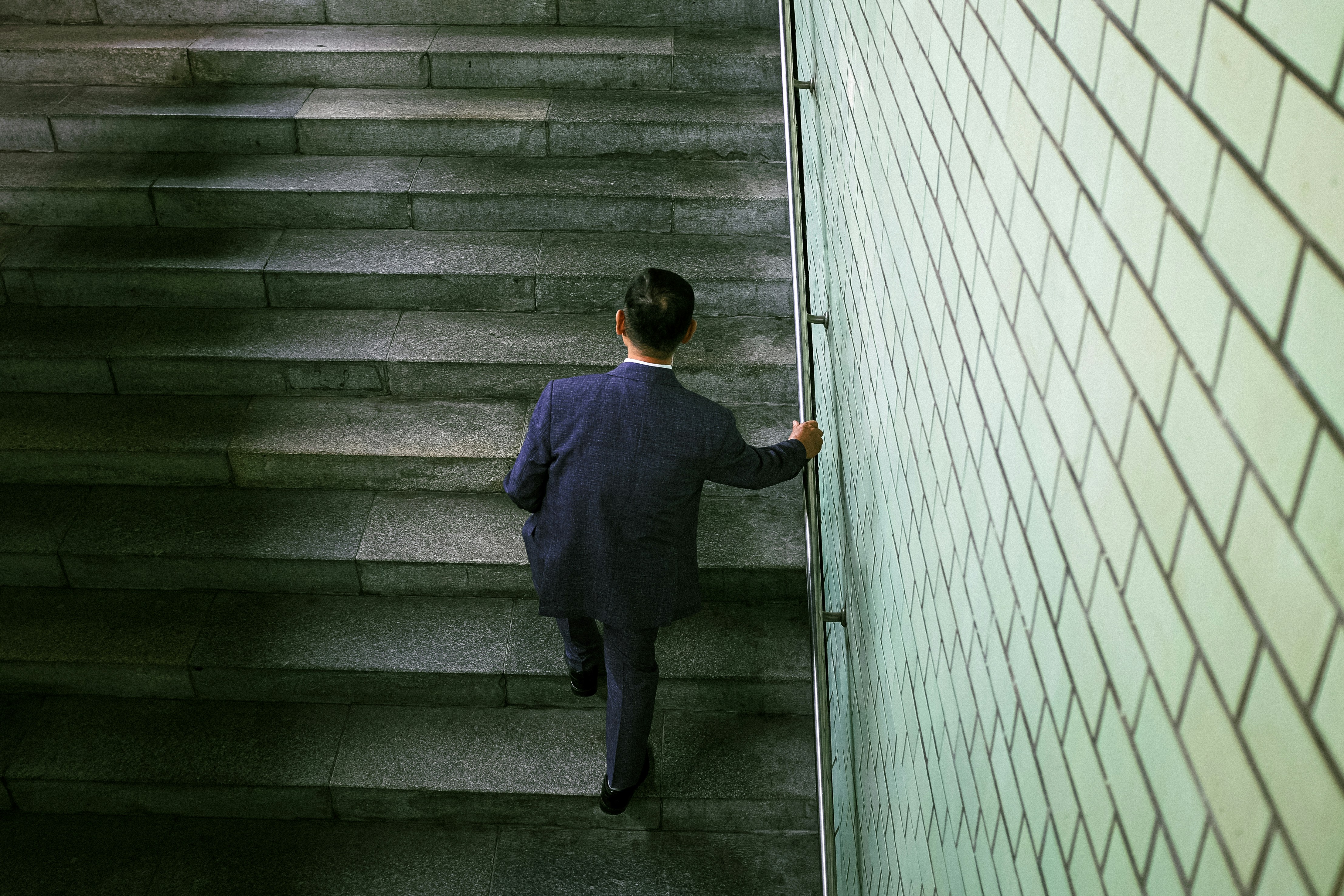 A business leader walking up a staircase alone, symbolizing personal growth, reflection, and the path of leadership development.