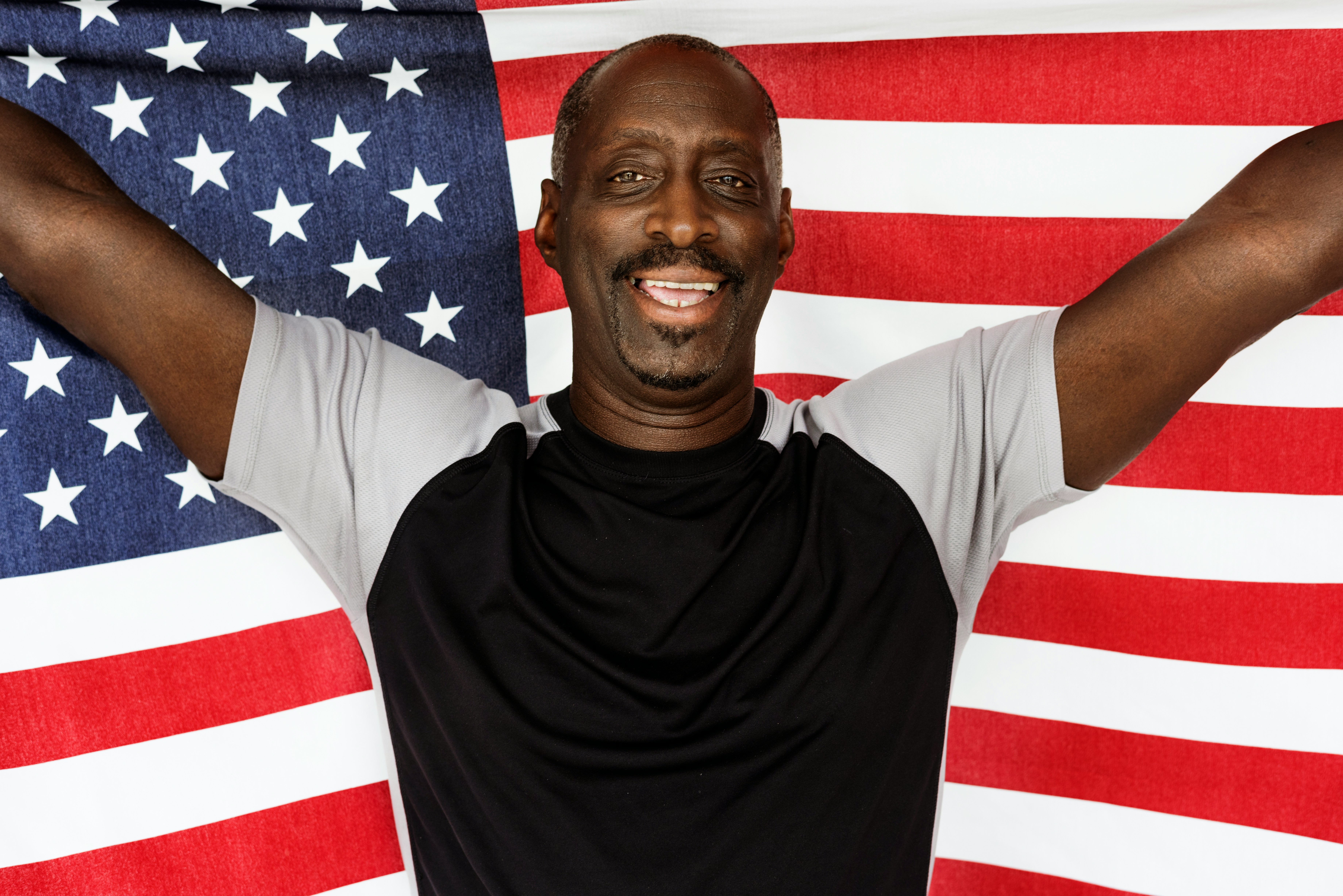 A happy man holding the American flag, symbolizing success with the help of an immigration consultant.