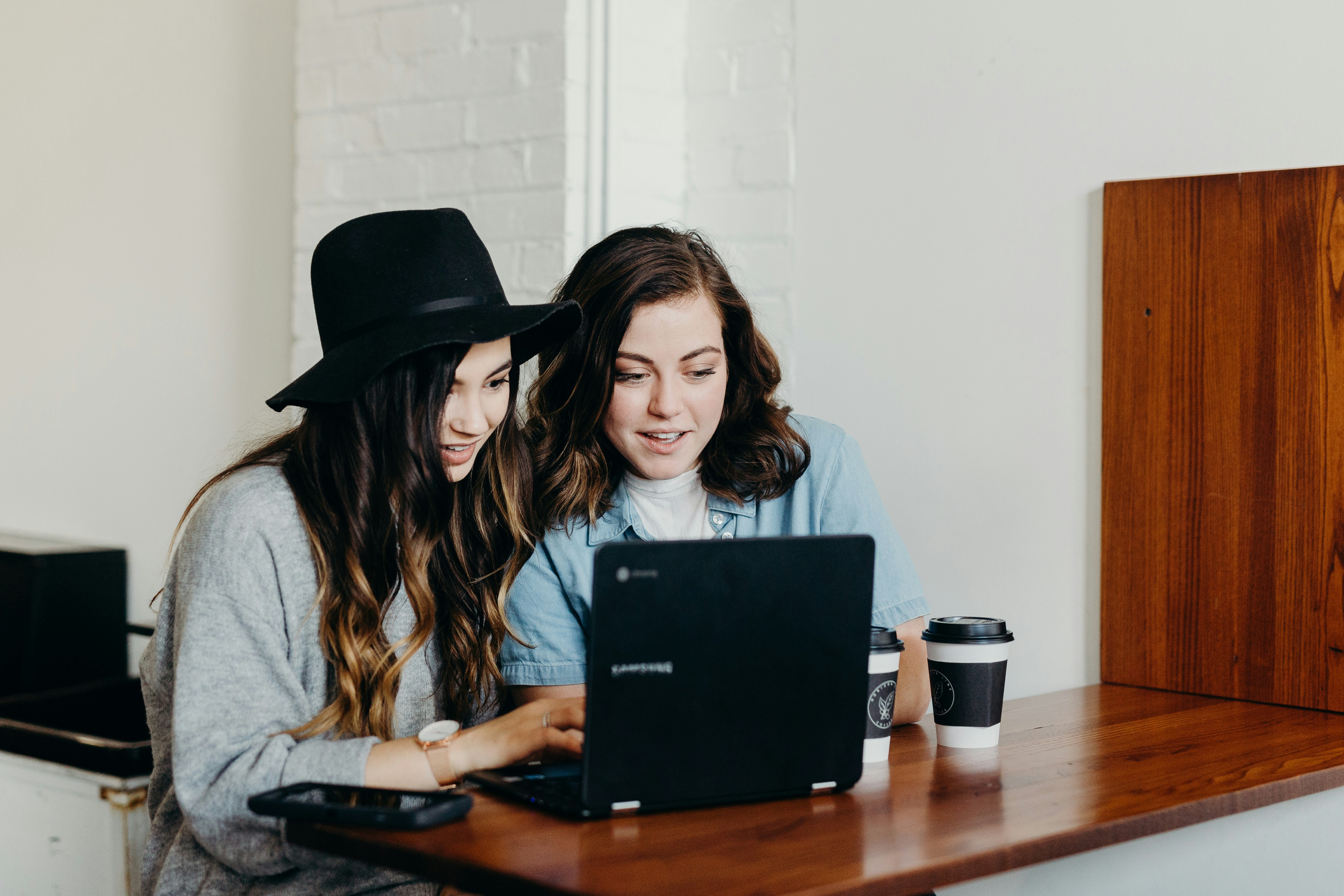Two women collaborating on a laptop, discussing success stories in professional growth.