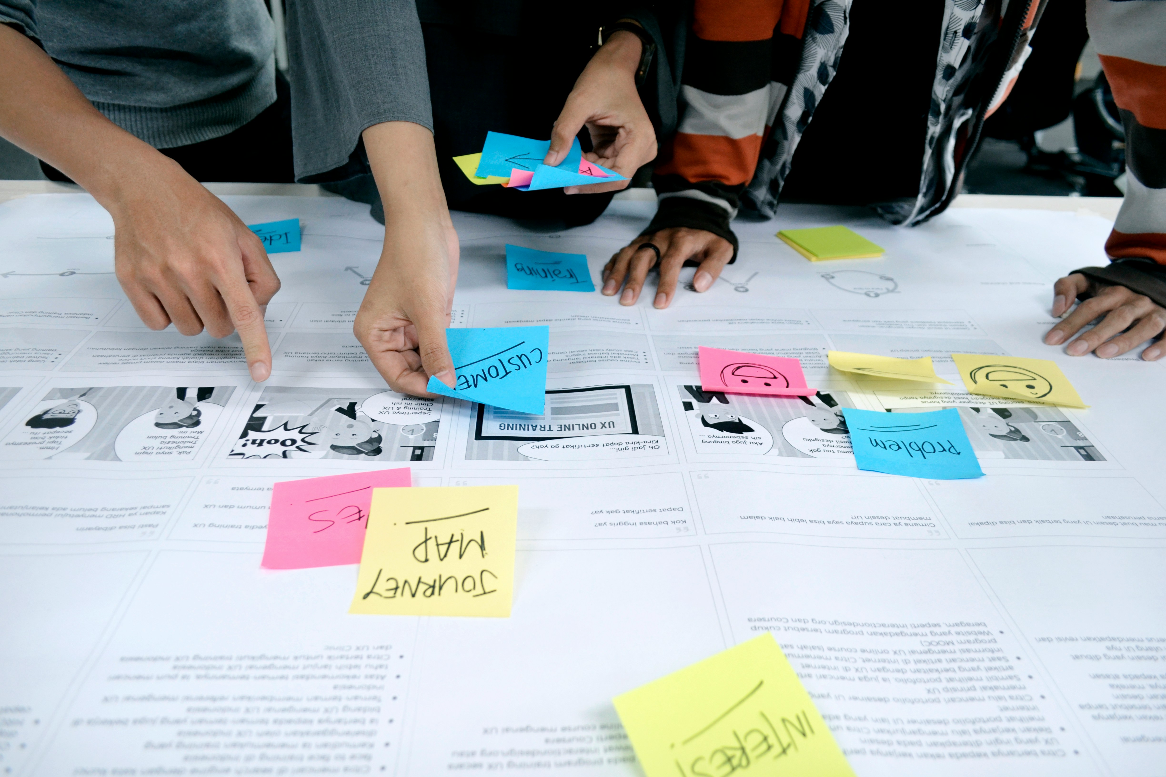 Close-up of a collaborative team workshop with hands arranging sticky notes on a planning board, symbolizing mentorship, guidance, and strategic team development.